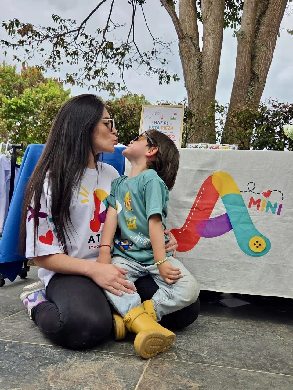 Laura dándole un beso a Lorenzo frente a la mesa de Mini Atelier